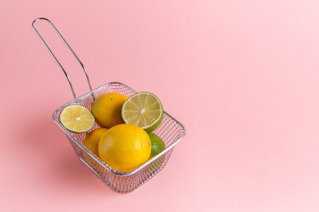 Front view of fresh lemons citruses inside fryer on pink wall