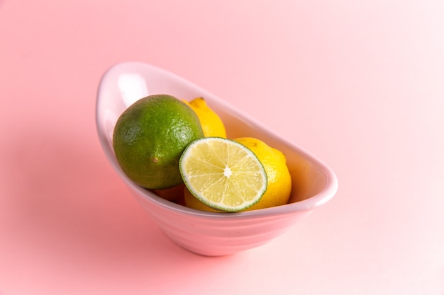 분홍색 벽에 접시 안에 슬라이스 라임과 신선한 레몬의 전면보기