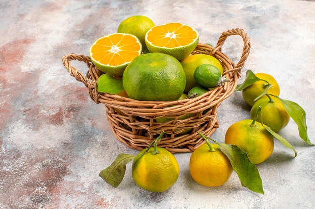 Front view fresh mandarines in wicker basket surrounded by mandarines on nude background