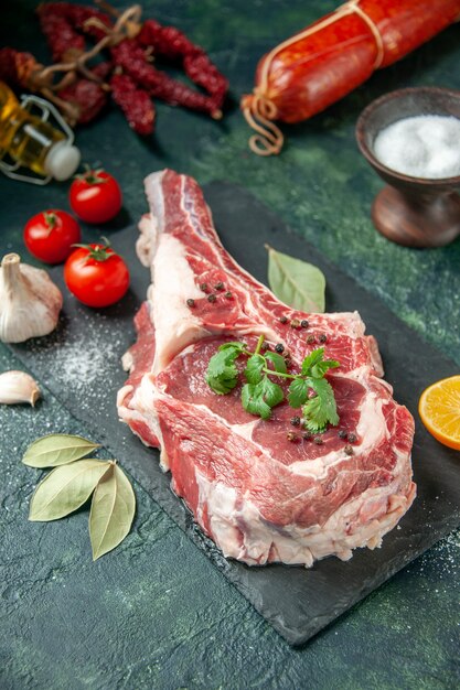Кусочек свежего мяса с помидорами и колбасой, вид спереди на темно-синей кухне, животное, корова, пищевой краситель, мясо, мясо, курица
