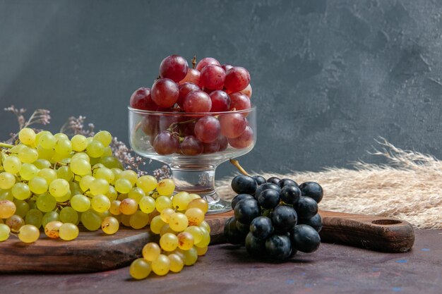 Вид спереди свежий спелый виноград разного цвета на темной поверхности вино свежий виноград плодовое дерево спелое растение