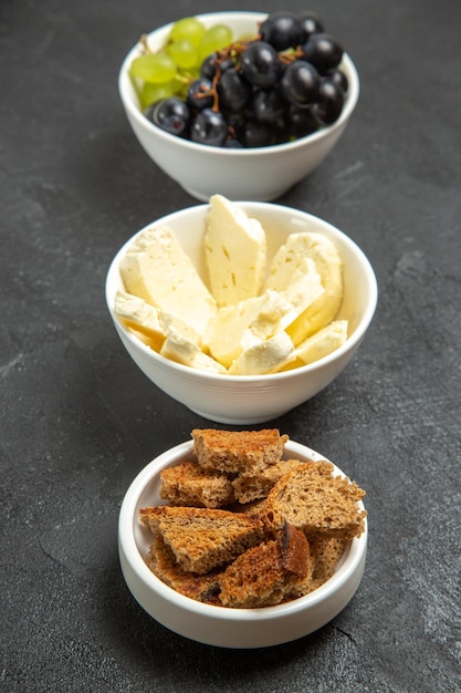 Front view fresh mellow grapes with white cheese and sliced dark bread on the dark background meal food dish milk fruits