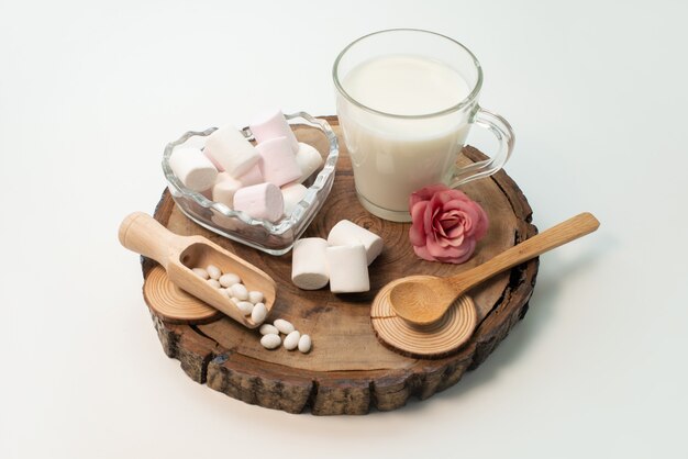 Вид спереди свежее молоко вместе с зефиром на коричневом деревянном на белом, сладкие конфеты