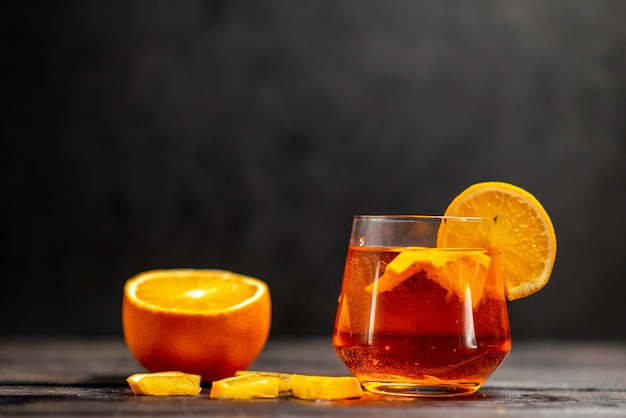 Free photo front view of fresh natural delicious juice in a glass with orange limes on dark table