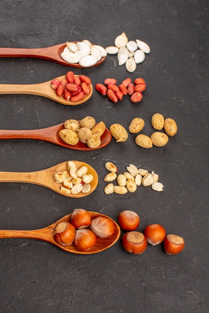 Front view of fresh nuts peanuts and other nuts on dark surface