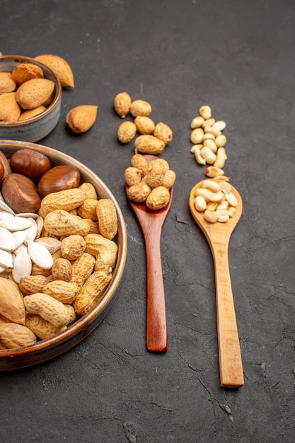 Front view of fresh nuts peanuts and other nuts on dark surface