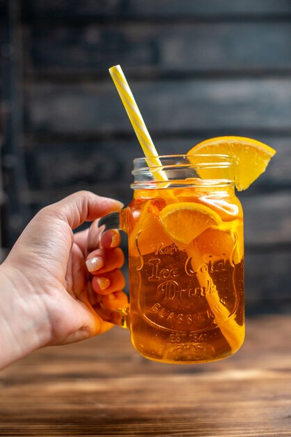 Свежий апельсиновый сок, вид спереди, внутри банки на темном баре, цветная фотография фруктов, коктейльный напиток