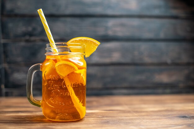 Свежий апельсиновый сок, вид спереди, внутри банки с соломинкой на темном баре, фруктовый цветной напиток, фото