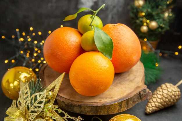 Вид спереди свежие апельсины вокруг елочных игрушек на темном фоне фруктовый тропический экзотический свежий сок