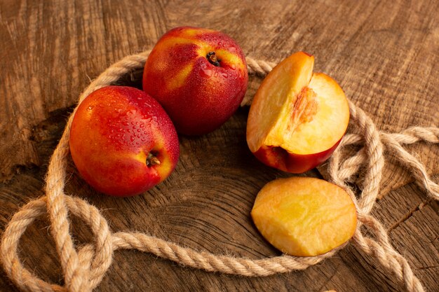 Front view fresh peaches whole and sliced on wooden desk