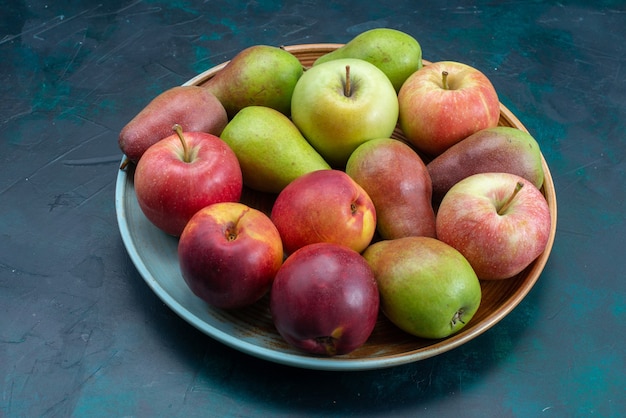 正面図紺色の机の上にリンゴと新鮮な梨フルーツ新鮮なまろやかな熟した甘い