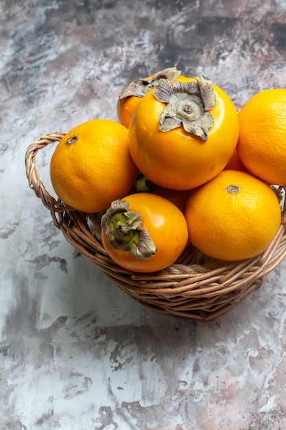 Front view fresh persimmons inside basket on a light table