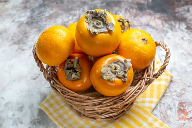 Front view fresh persimmons inside basket on light table