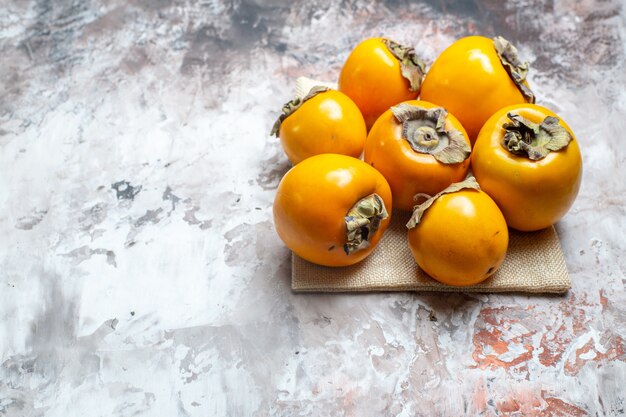 Front view fresh persimmons on a light table color fruits tree healthy life photo ripe