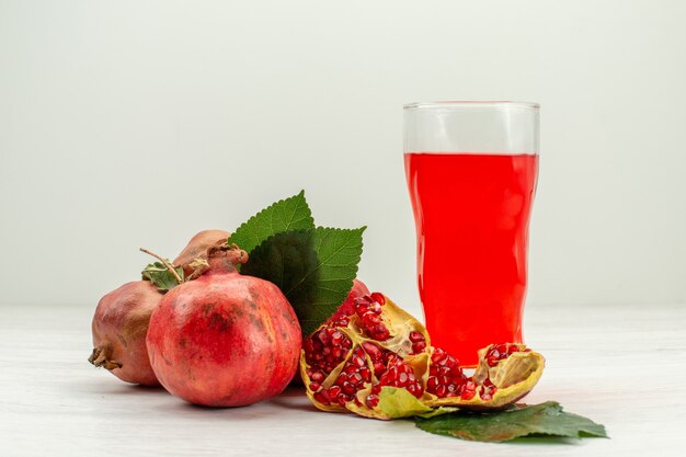 Front view fresh pomegranate juice with fresh pomegranates on the white desk