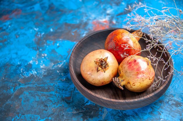 Front view fresh pomegranates in a bowl on blue