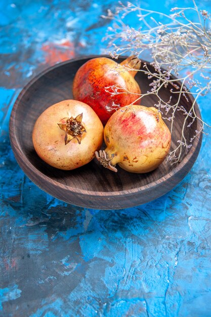 Front view fresh pomegranates in wooden bowl on blue