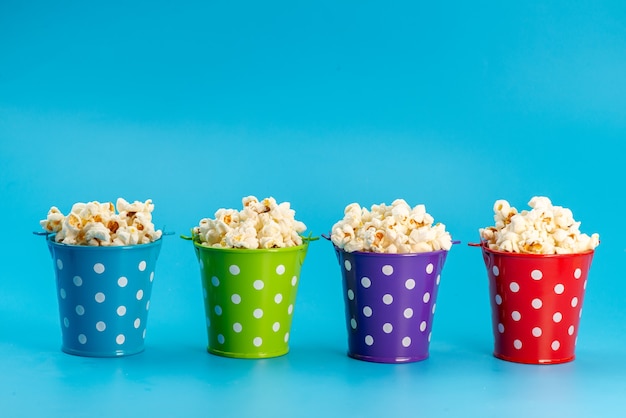 A front view fresh popcorn inside colorful baskets on blue, cinema movie snack corn seeds