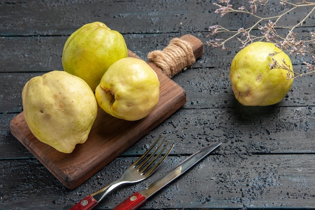 Vista frontale mele cotogne fresche frutti dolci e aspri su una pianta da scrivania blu scuro albero da frutto fresco e acido maturo