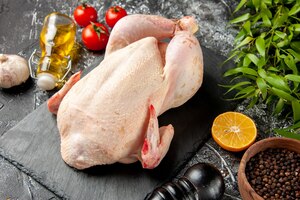 Вид спереди свежая сырая курица с помидорами на светлой-темной кухне еда фото животных курица мясо цвет фермерская еда