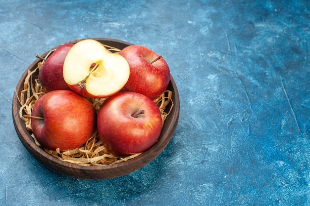 Вид спереди свежие красные яблоки внутри тарелки на синей поверхности