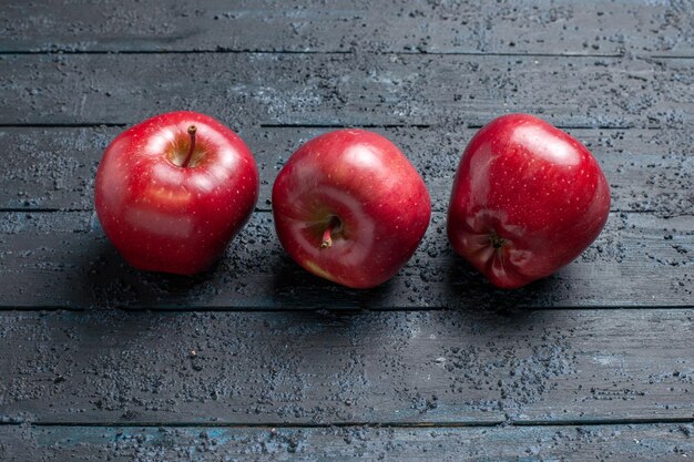 正面図新鮮な赤いリンゴの熟したまろやかな果物を紺色の机の上にたくさんの果樹の赤い新鮮な植物の色