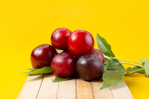 Вид спереди свежей красной вишни, спелой и кислой на желтом, фруктовом летнем цвете