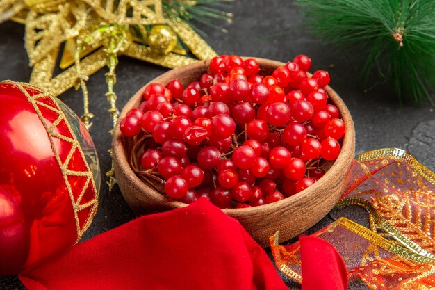 Front view fresh red cranberries around christmas toys on dark background color xmas holiday fruit berry