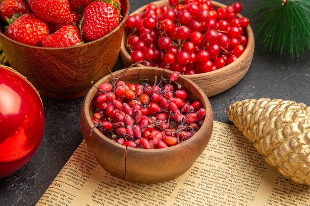 Front view fresh red cranberries with other fruits around christmas toys on the dark background color xmas holiday fruit berry