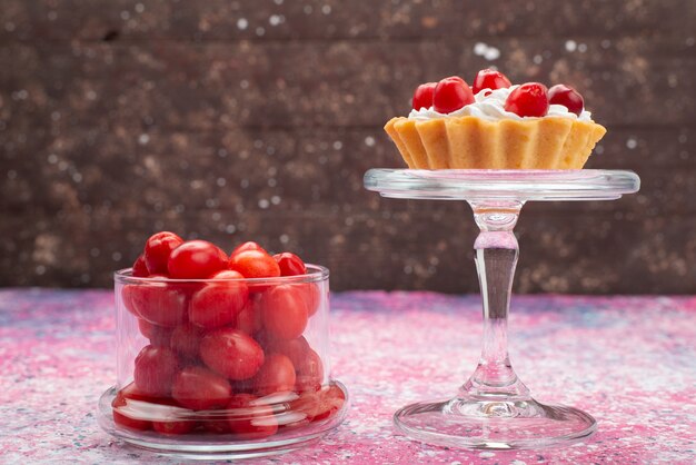 Front view fresh red fruits mellow sour and ripe inside transparent glass with cakes on the bright desk fruit berry fresh