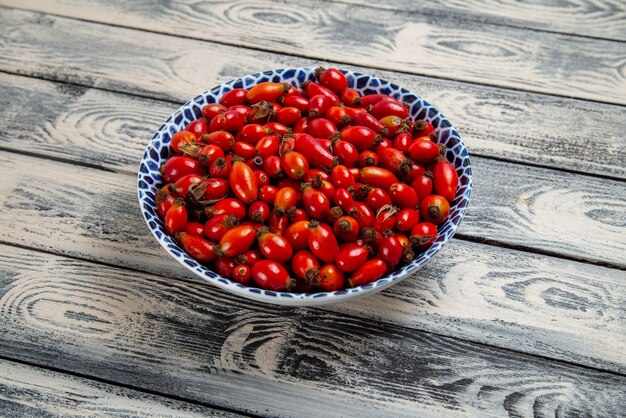 Front view fresh red fruits ripe and sour berries inside plate on the grey rustic surface fruits berry color vitamine tree plant