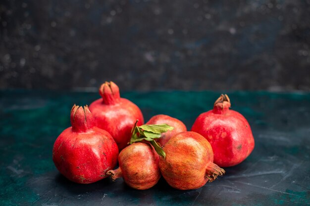 Front view of fresh red pomegranates on dark surface