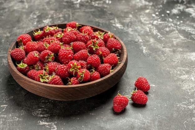 Free photo front view fresh red raspberries inside plate on a grey photo color berry fruit color cranberry wild