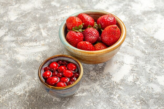 白い表面の小さな鍋の中の新鮮な赤いイチゴの正面図フルーツ赤いベリー