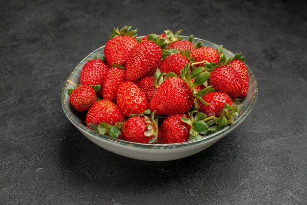 Вид спереди свежей красной клубники внутри тарелки на сером фоне цвет сока дерева дикий вкус ягоды лето