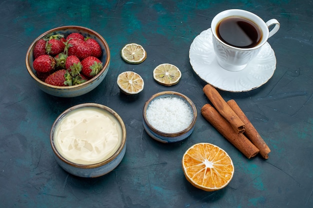 Front view of fresh red strawberries with cinnamon and cup of tea on blue desk