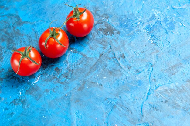 파란색 탁자에 있는 신선한 빨간 토마토 전면 보기