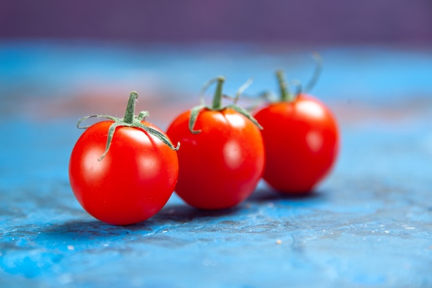 파란색 탁자에 있는 신선한 빨간 토마토 전면 보기