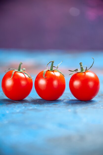 파란색 탁자에 있는 신선한 빨간 토마토 전면 보기