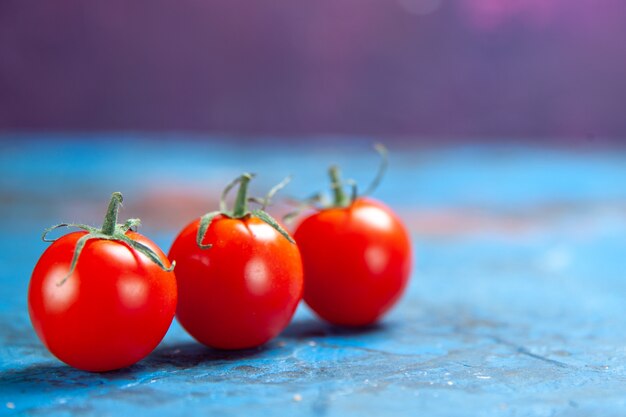 파란색 탁자에 있는 신선한 빨간 토마토 전면 보기