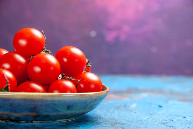 Вид спереди свежие красные помидоры внутри тарелки на синем столе