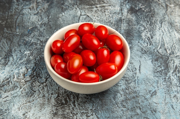 暗い光の背景のプレート内の新鮮な赤いトマトの正面図