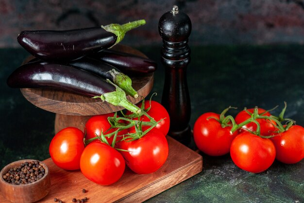 暗い背景にナスと正面図新鮮な赤いトマト