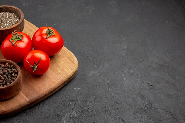 暗いスペースに調味料を入れた正面の新鮮な赤いトマト