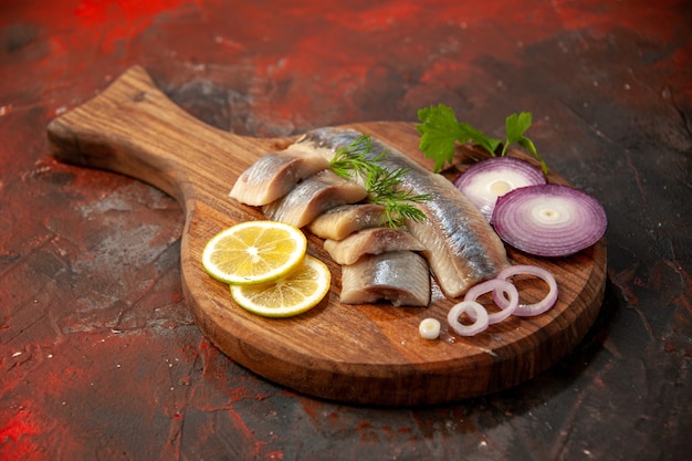 Вид спереди свежей нарезанной рыбы с луковыми кольцами и лимоном на темной муке, мясных закусках из морепродуктов, цветное фото
