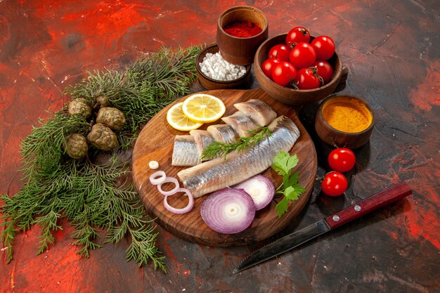 Вид спереди свежая нарезанная рыба с приправами, помидорами и сыром на темных морепродуктах цветное фото закуска мясной салат