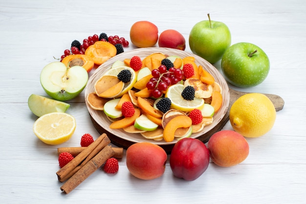 A front view fresh sliced fruits colorful and mellow with cinnamons on the wooden desk and white background fruits color food photo