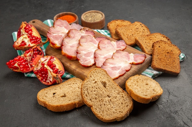 Front view fresh sliced ham with seasonings bread and pomegranates on dark meal color food raw photo meat