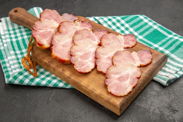 Вид спереди свежей нарезанной ветчины на деревянном столе и серая еда, фото, мясо сырого цвета свиньи