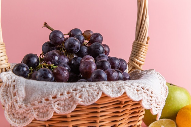 Front view of fresh sour grapes inside basket on pink wall